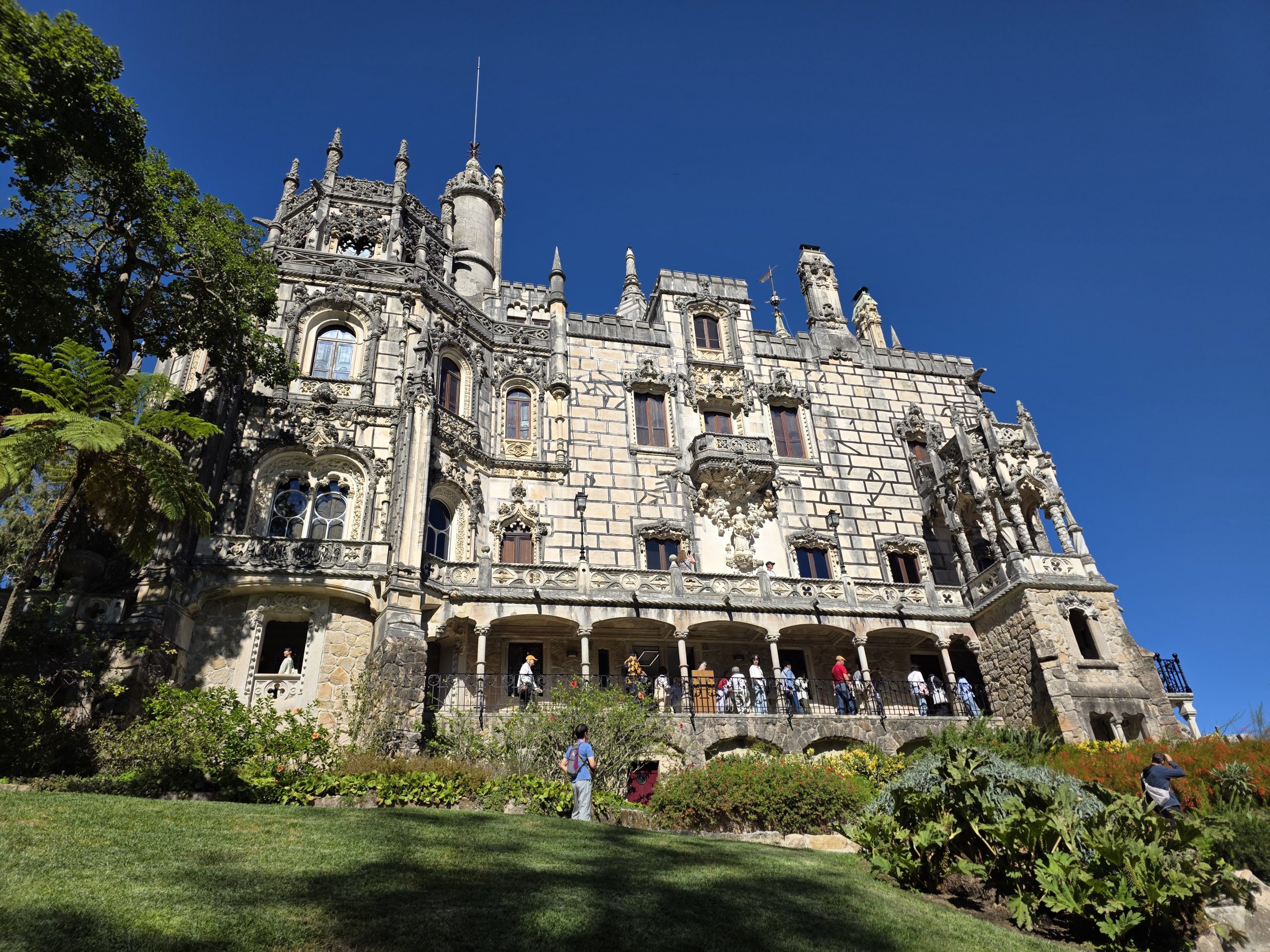 Low-angle view of Regaleira Palace showing carved windows, balconies, and pinnacles.