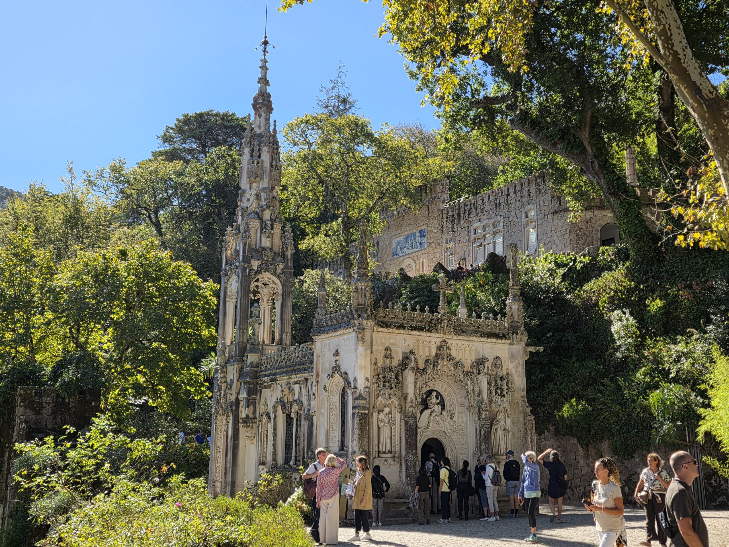 Ornately decorated chapel with a tall spire surrounded by trees at Quinta da Regaleira.